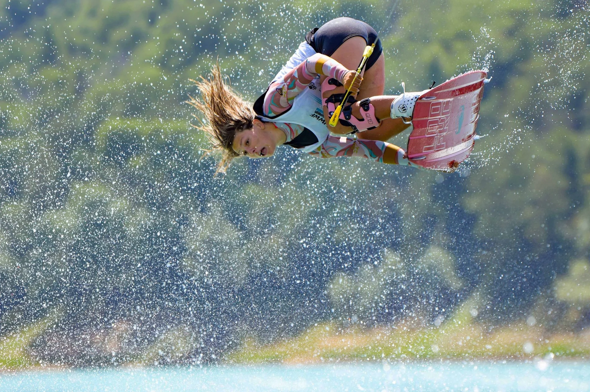 Alizé Piana tucked mid-air through a curtain of spray