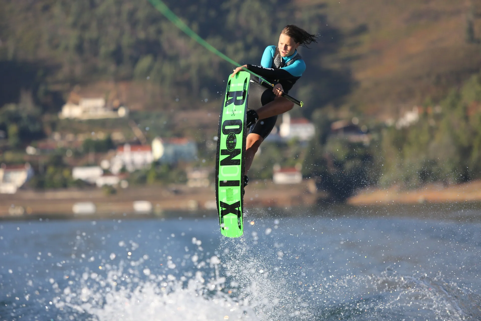 Anna-Mariia Kushkovskaia grabbing her board mid-air behind the boat