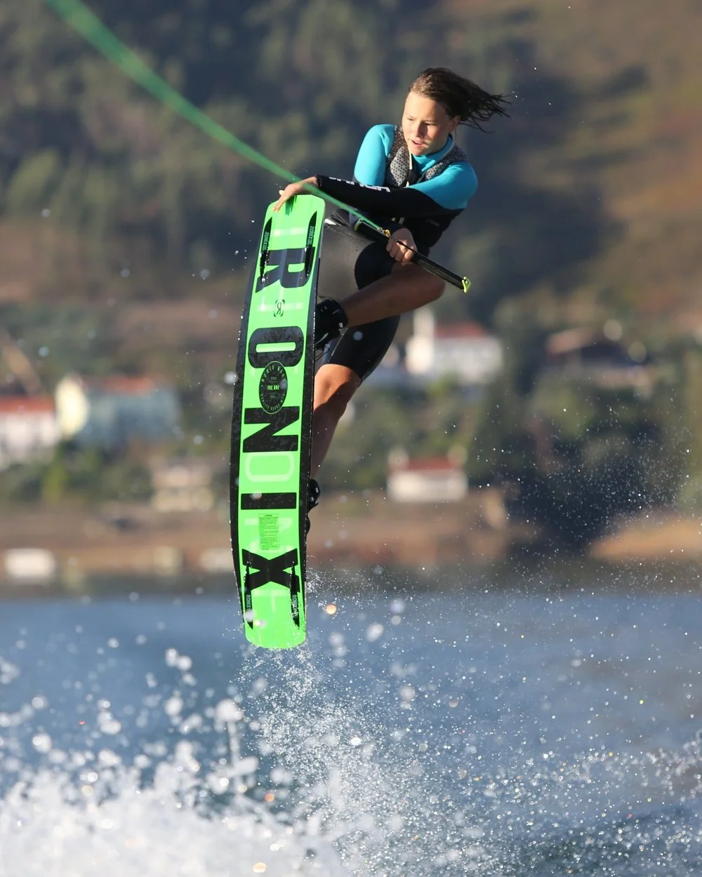 Anna-Mariia Kushkovskaia grabbing her board mid-air behind the boat